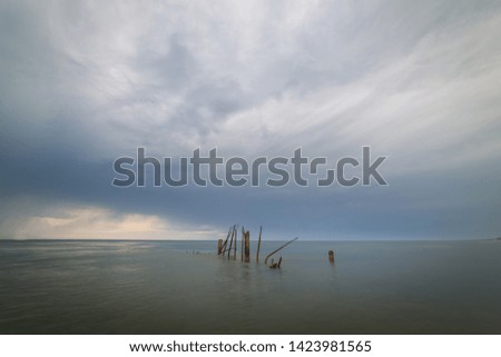 Thunderstorm and the old rusty breakwater in the Baltic sea early in the morning.