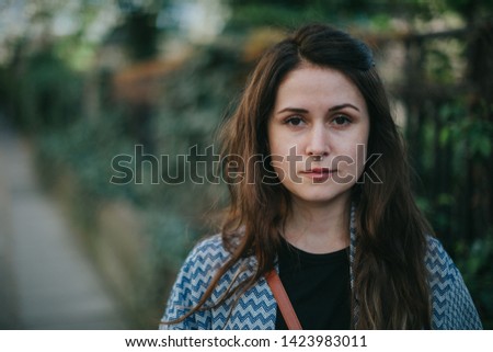 Picture of a beautiful young woman with nose piercing, posing on the street.