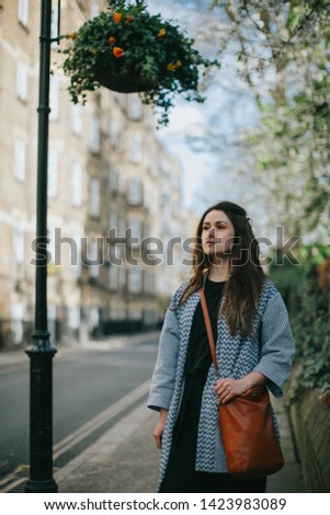 Picture of a beautiful young woman with nose piercing, posing on the street.