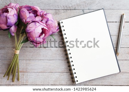 Flat lay of Purple flower, blank notepad and pen on wooden table background with copy space. Conceptual