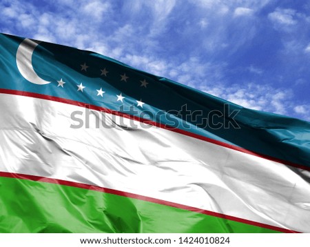 waving flag of Uzbekistan close up against blue sky