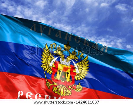 waving flag of the Lugansk People's Republic close up against blue sky