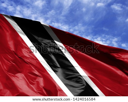 waving flag of Trinidad and Tobago close up against blue sky