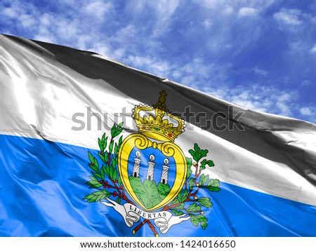 waving flag of San marino close up against blue sky
