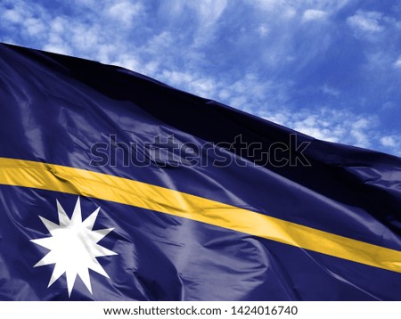 waving flag of Nauru close up against blue sky