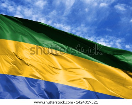 waving flag of Gabon close up against blue sky