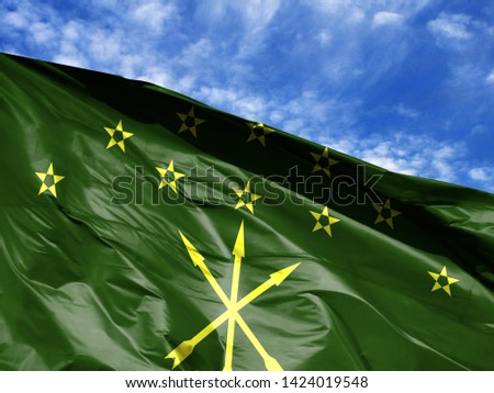 waving flag of Adygea close up against blue sky