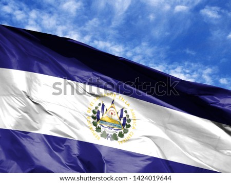 waving flag of El Salvador close up against blue sky