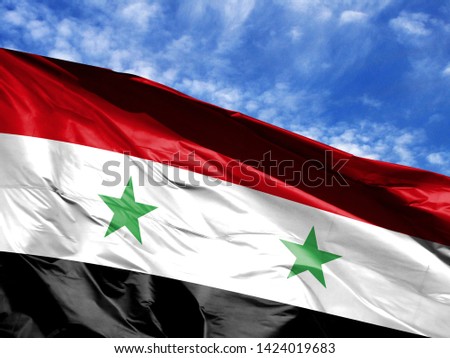 waving flag of Syria close up against blue sky