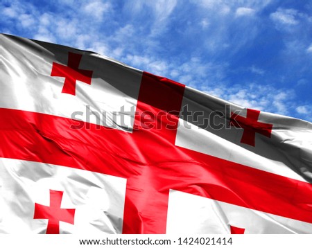 waving flag of Georgia close up against blue sky