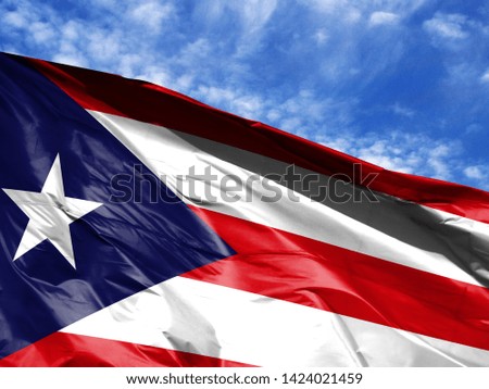 waving flag of Puerto Rico close up against blue sky