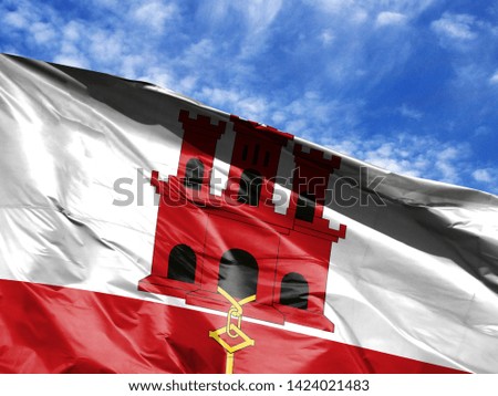waving flag of Gibraltar close up against blue sky
