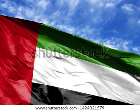 waving flag of United Arab Emirates close up against blue sky