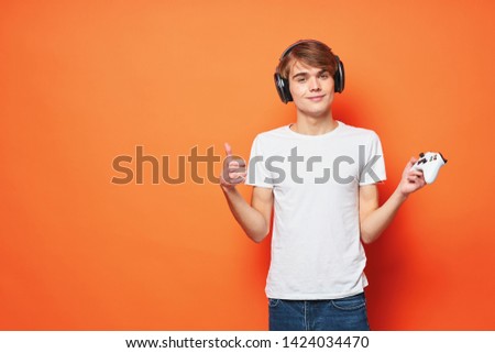 Cute guy with a joystick in the hands of a game console fun orange background
