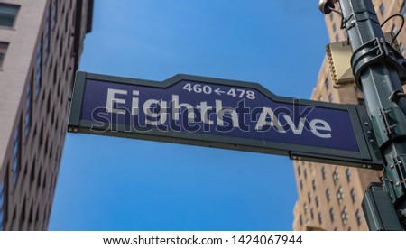 Eighth ave street sign, Manhattan New York downtown. Blue sign on blur buildings facade and blue sky background,