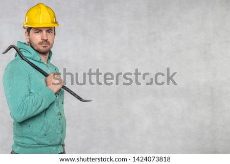the construction worker holds a work tool in his hands, a crowbar