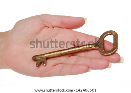 Female hand with an old metal key on a white background