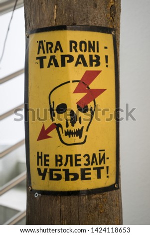 The inscription in Estonian and Russian. "Do not climb will kill!" The label is hanging on power poles.