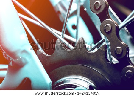 Sprocket with chain and dark color of the rear wheel of the Bicycle. The background is blurred. The spokes are visible close up.