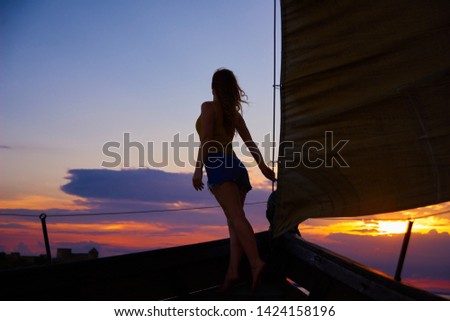 silhouette of a girl on board a sailboat on the background of a bright sunset