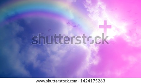 Imagine Christian Cross that illuminates the beautiful rainbow sky on a fluffy white cloud. And the light that shines down among the birds that fly in the sky As love and freedom of Jesus