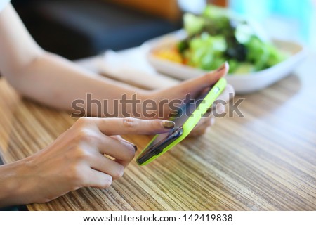 female using mobile phone on food table Royalty-Free Stock Photo #142419838
