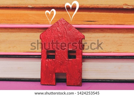 Home sweet home, house wood with heart shape on on pink background and books background