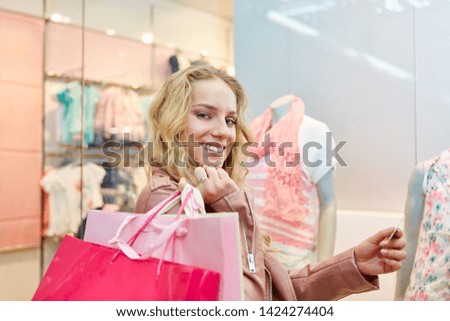 Young smiling woman with bags and with credit card while shopping