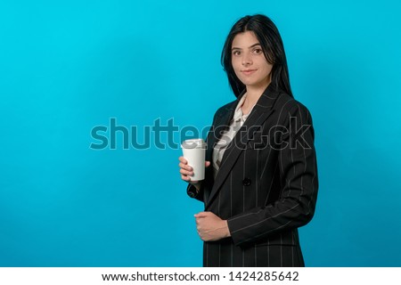 young woman classic dressed with cup of coffee or tea on a blue background. cup of drink