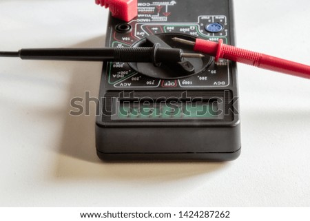 digital multimeter with red black test leads on a white background