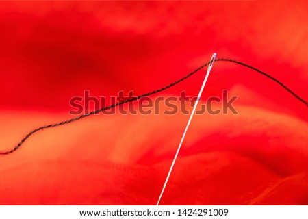 Black thread and needle  on red background