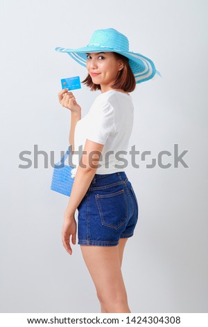 Summer travel, Pretty Asian woman wearing hat with holding Credit card on wall white, Online business concepts and holidays