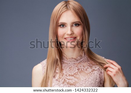 Young blond lady in  dress posing on grey background