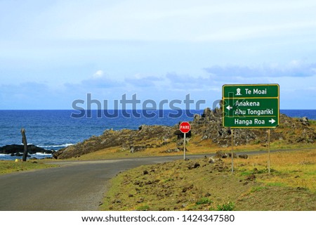 Roadside Signpost for Anakena beach, Ahu Tongariki, Hanga Roa town center and Stop(PARE) sign against Pacific ocean, Easter Island, Chile