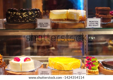 Showcase variety Japanese cake, closeup and selective focus various dessert around on shelf with tag of name and price, beautiful display of bakery business concept