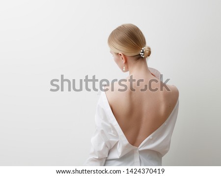 Minimalist photo , Fashionable girl in stylish summer things - white shirt . View from the back. Earrings, a ring . Street fashion , blogger style . Beauty . Minimalist Fashion clothes Royalty-Free Stock Photo #1424370419