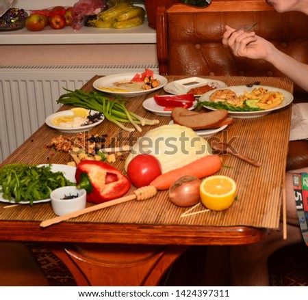 woman at home having lunch at the table next to raw vegetables for taking pictures