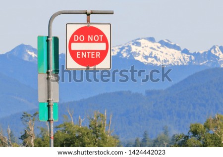 An English sign states do not enter with beautiful snow capped mountains in the background. 