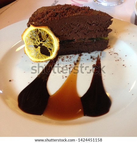 Macro photo food dessert chocolate cake. Texture background chocolate cake with caramel syrup. Image of a piece of chocolate cake with lemon on a white plate
