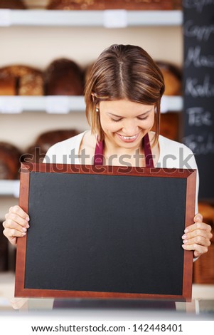 Bakery worker holding up a blank slate or small chalkboard for your advertisement or text
