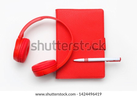 Red headphones and red notebook with pen