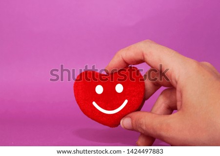 closeup hand holding heart cotton shape with happy face.  Service rating, satisfaction concept