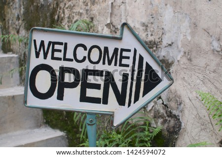 Close up picture of a "Welcome / Open" arrow sign placed in front of a Cafe in Kuala Lumpur