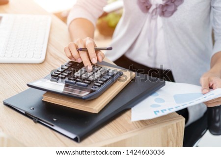 Woman accountant working on accounts in business analysis with graphs and document  financial data report with laptop computer at office, business concept.