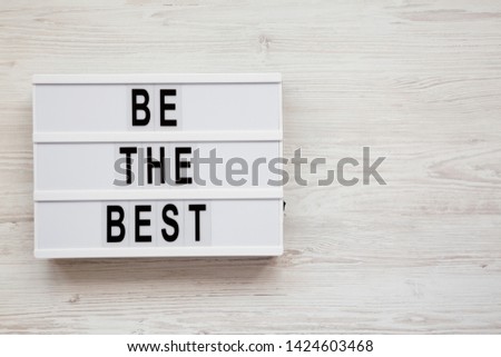 'Be the best' words on a modern board on a white wooden background. Flat lay, overhead, top view. Copy space.