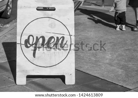 Wooden standing Open sign on sidewalk outside a business