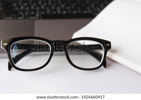 Eyeglasses on office table in the background of notebook and computer.