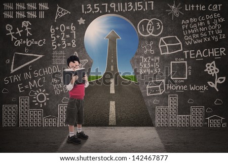 Boy is reading book with chalkboard and success road via keyhole