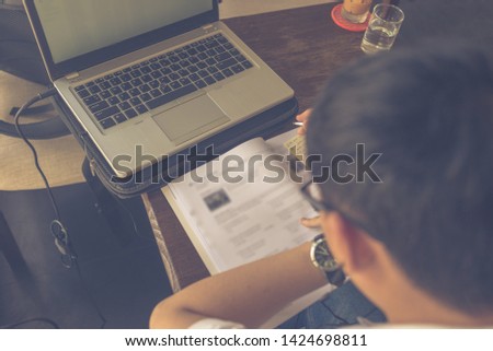 Rear view of Asian studying English with laptop and workbook
