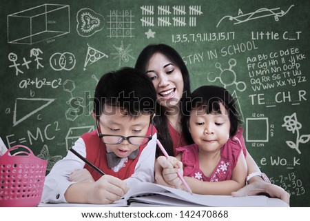 Close-up of teacher and children writing in classroom